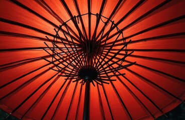 Red umbrella interior shows radial structure and fabric texture. Asian restaurant decor detail provides exotic visual element. Sunlight shines through paper material creating patterns.