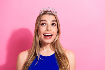 Young woman with tiara in blue top smiles against pink background for lifestyle fashion beauty and celebration © deagreez