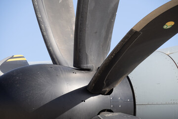 Macro view of propeller blades connected to the spinner hub of a turboprop engine showing aerodynamic contour and composite surface texture