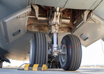 Detailed view of aircraft nose landing gear showing open bay panels and red remove before flight tags
