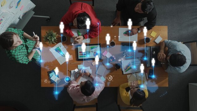 Overhead view of a collaborative team working in a modern office space, integrating digital elements to enhance communication and innovation during meetings. Raster - Powered by Adobe