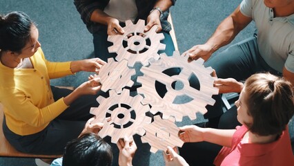 Top view of smart business people joining and gathering white gear together. Aerial view of diverse...