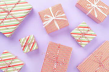 Obraz premium Many striped Christmas gift boxes on color background, top view