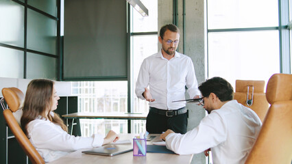 Team members engage in a business meeting in a contemporary office space, discussing strategies and sharing ideas while seated at a conference table.
