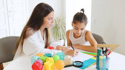 A speech therapist guides a young girl in a productive session, actively engaging her with colorful...