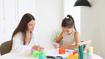 Speech therapist engages with child using colorful toys and art supplies in a bright, modern...