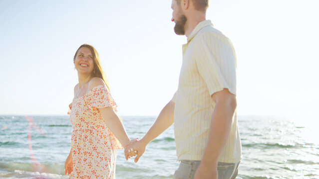 Couple enjoys a romantic stroll on the beach during a sunny day by the ocean, creating memories together and embracing the moment