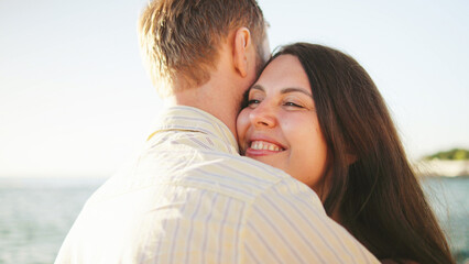 Fototapeta premium Couple enjoying a warm embrace on a sunny beach with gentle wave
