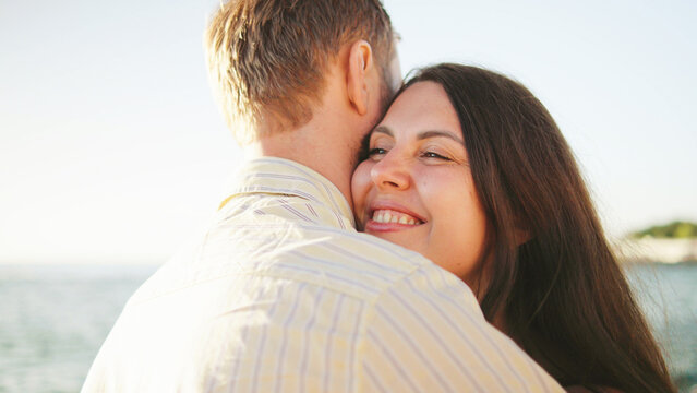 Couple enjoying a warm embrace on a sunny beach with gentle wave