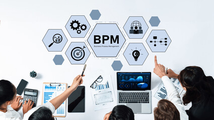 A diverse team collaborates on business process management strategies using charts and technology, showcasing teamwork and innovation in a modern office environment. Trope