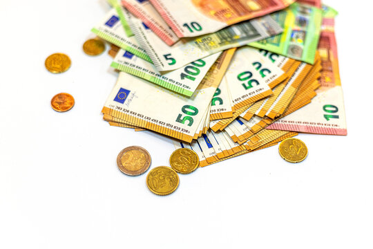 Collection of euro banknotes and coins arranged on a white surface for financial or economic representation