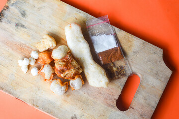 Crackers, cuanki, noodles, and complete dry seblak seasoning on a wooden tray