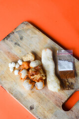 Crackers, cuanki, noodles, and complete dry seblak seasoning on a wooden tray