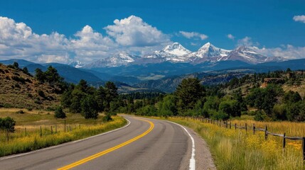 Scenic Roadway with Snow-Capped Mountains and Lush Greenery under a Bright Blue Sky in a Beautiful Outdoor Landscape