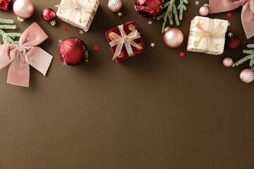Christmas flat lay with gift boxes, red and pink ornaments, pine branches and star confetti on...