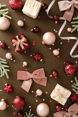 Christmas flat lay with ornaments, pine branches and gift boxes on brown background