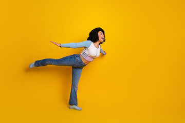 Cheerful young woman posing in casual outfit against a vibrant yellow background showing a joyful...