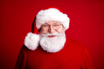 Santa smiles in a cozy red sweater and hat against a bright red background creating a warm festive portrait for Christmas promotions and holiday campaigns