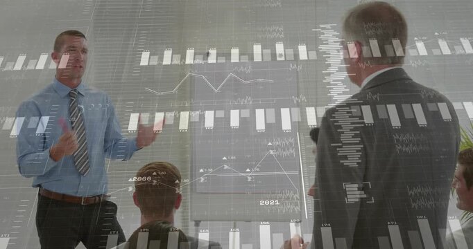 Male presenter pointing marker flipchart, causing graphs, senior mgr rising with mic explaining ROI