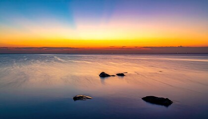 Vibrant Sunset Over Tropical Ocean Reflecting Colorful Sky with Calm Water and Distant Island Silhouettes on the Horizon