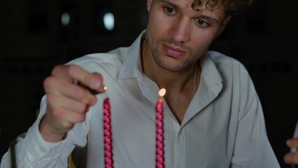 Close up of young man lighting candles sitting on romantic date in evening outdoors with pretty attractive woman drinking red wine. Happy couple lovers spending night together.