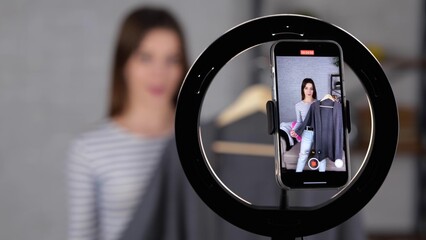 Young female blogger using smartphone and recording video for her followers while showing gray sweater at home. Pretty woman recording video. Small business, online market concept. video
