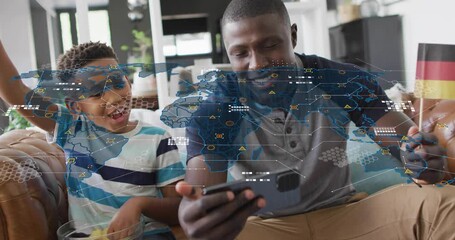 Father pointing phone and son waving Brazil flag while watching sports, map overlay linking flags - Powered by Adobe