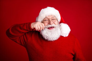 Santa Claus in a red sweater and hat smiles warmly against a bold red background ready for Christmas season