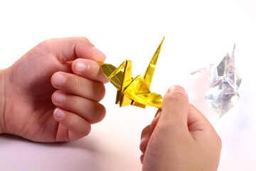 折り鶴を持つ子どもの手
