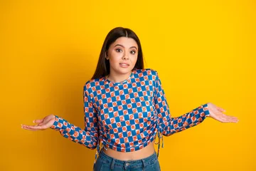 Fotobehang Muziek Young woman in a bold checkered top poses with open hands against a bright yellow background for a bold fashion lifestyle shot  © deagreez