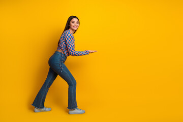 Young woman in casual chic outfit smiles as she poses against a bold yellow background for a lively fashion lifestyle image