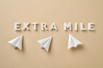 Origami Paper Lettering Spelling EXTRA MILE on Beige Surface