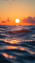 Vibrant orange sunset over the ocean with gentle waves reflecting the warm light creating a serene and beautiful seascape at dusk