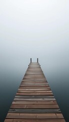 Fototapeta premium Distant view of a wooden dock disappearing into a misty lake on a foggy morning, landscape, fog