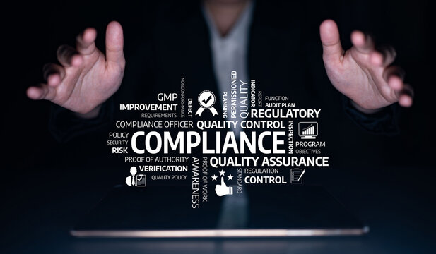 A pair of hands reaches out towards floating words representing compliance, quality assurance, and regulatory frameworks, set against a dark backdrop, emphasizing business integrity. Tessel