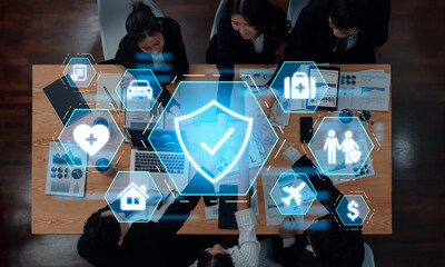 A diverse team discusses digital insurance solutions in a modern office setting, showcasing graphic icons that represent various aspects of coverage and security. Trope