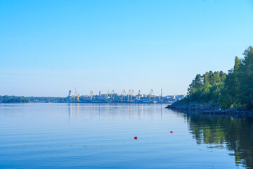 Calm lake with forest shoreline under clear blue sky at sunrise