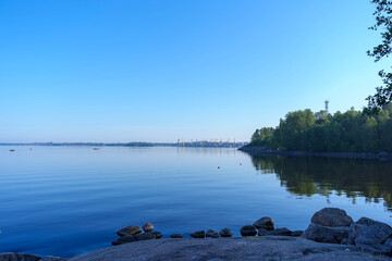 Calm lake with forest shoreline under clear blue sky at sunrise