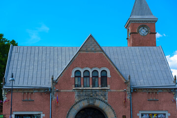 Historic brick building with clock tower and steep roof under blue sky
