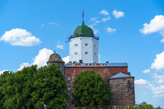Medieval white castle tower with green dome under blue summer sky