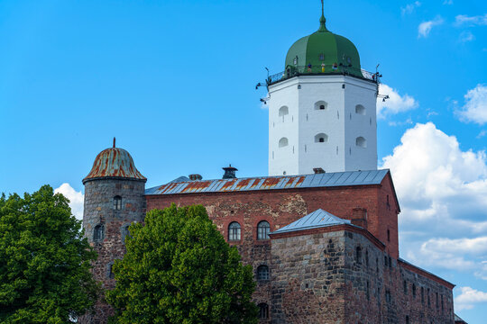 Medieval white castle tower with green dome under blue summer sky