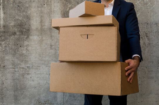 Frontal photograph with copyspace of a man carrying boxes with no visible labels - Powered by Adobe