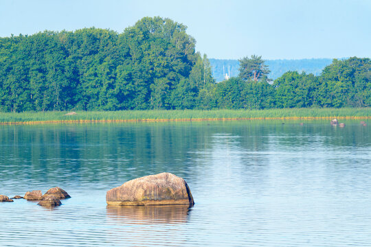 Tranquil lake with rocky shoreline and small islands at dusk - Powered by Adobe