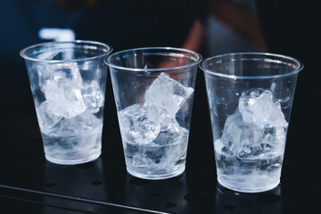 Barman mixing liquor beverages and alcohol drinks in plastic cups, bartender working, beautiful row line of different coloured cocktails on open air summer party in a bar, catering on banquet event