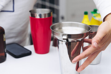 Barman mixing liquor beverages and alcohol drinks in plastic cups, bartender working, beautiful row line of different coloured cocktails on open air summer party in a bar, catering on banquet event