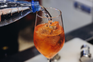 Barman mixing liquor beverages and alcohol drinks in plastic cups, bartender working, beautiful row line of different coloured cocktails on open air summer party in a bar, catering on banquet event