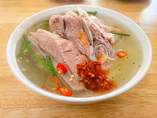 Pork rib noodle soup from Da Lat, topped with chili paste, green onions, and pepper—rich broth and bold flavors in a cozy mountain setting