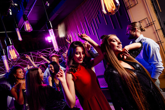 Energetic party scene of friends dancing at a nightclub with neon lights smiling crowd and festive vibe at a big event - Powered by Adobe