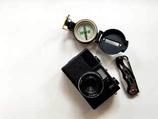 compass, old camera and folding knife on white surface. suggesting an emphasis on travel or exploration essentials theme.
