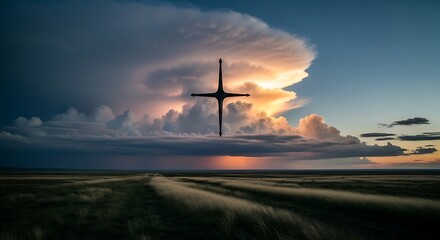 Obraz premium Dramatic Sky with Cross Silhouette Over Landscape at Sunset.